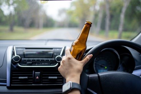man driving while drinking alcohol